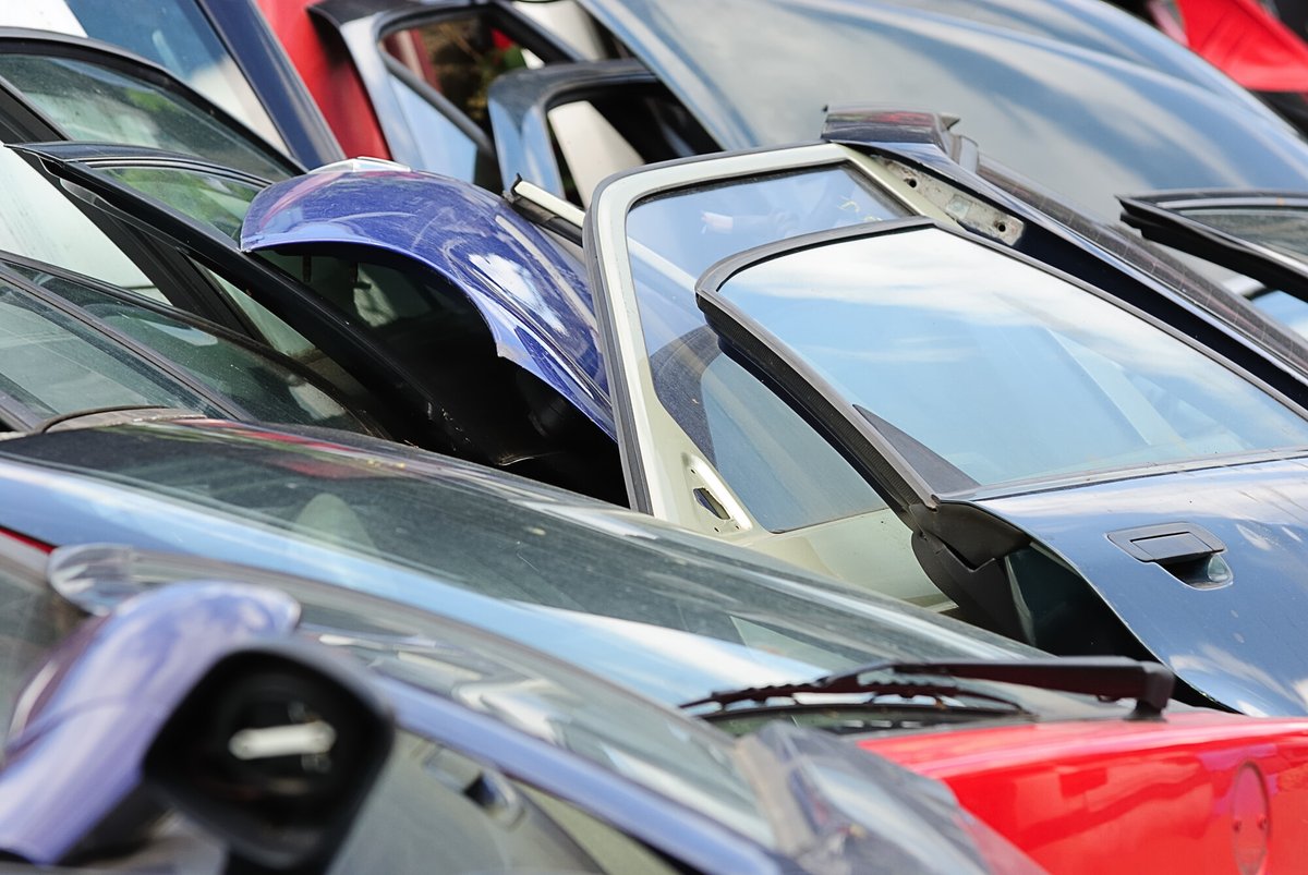 Fila di auto in attesa di demolizione con portiere aperte